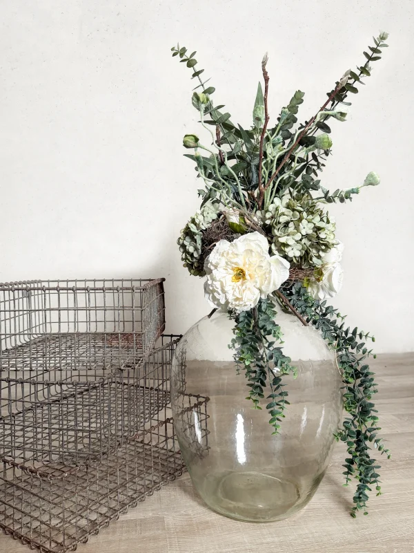 Blumenarrangement in altem Weinballon